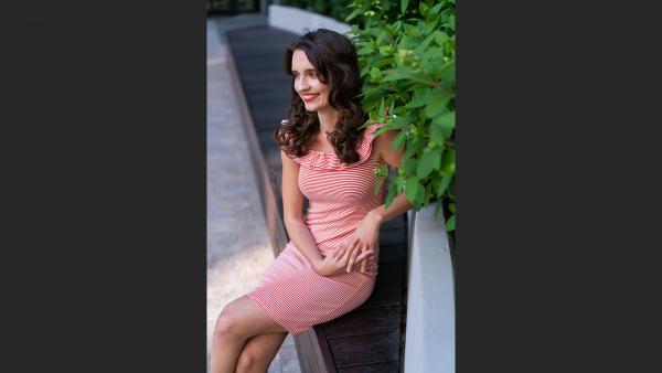 Young female on bench next to bush