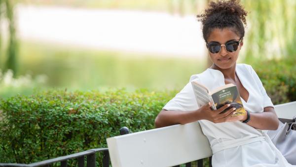 Woman on bench in park reading a book